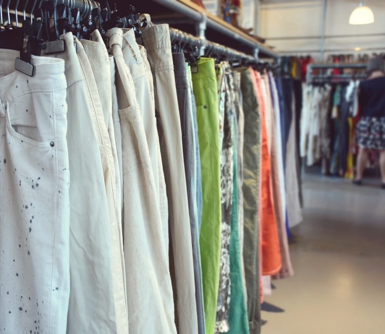 Clothing in vintage clothing shop. Woman shopping on the background.